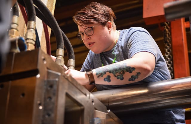 Industrial Maintenance Technician performing routine maintenance on injection molding machine