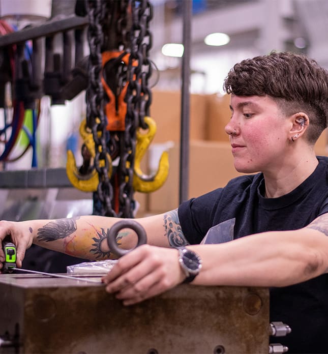 Grace measures a die block during her shift at Tool Gauge