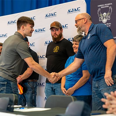 An Elma AJAC Youth Apprentice shakes hands with his hiring employer