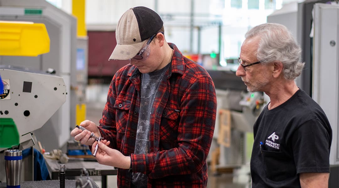 WorkEx Intern and his supervisor inspect a machined part at Automatic Products in Sumner, Washington