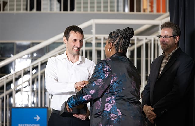 Sergiu Copaceanu greets Lynn Strickland on stage during AJAC's 2023 Apprenticeship Graduation Ceremony at The Museum of Flight