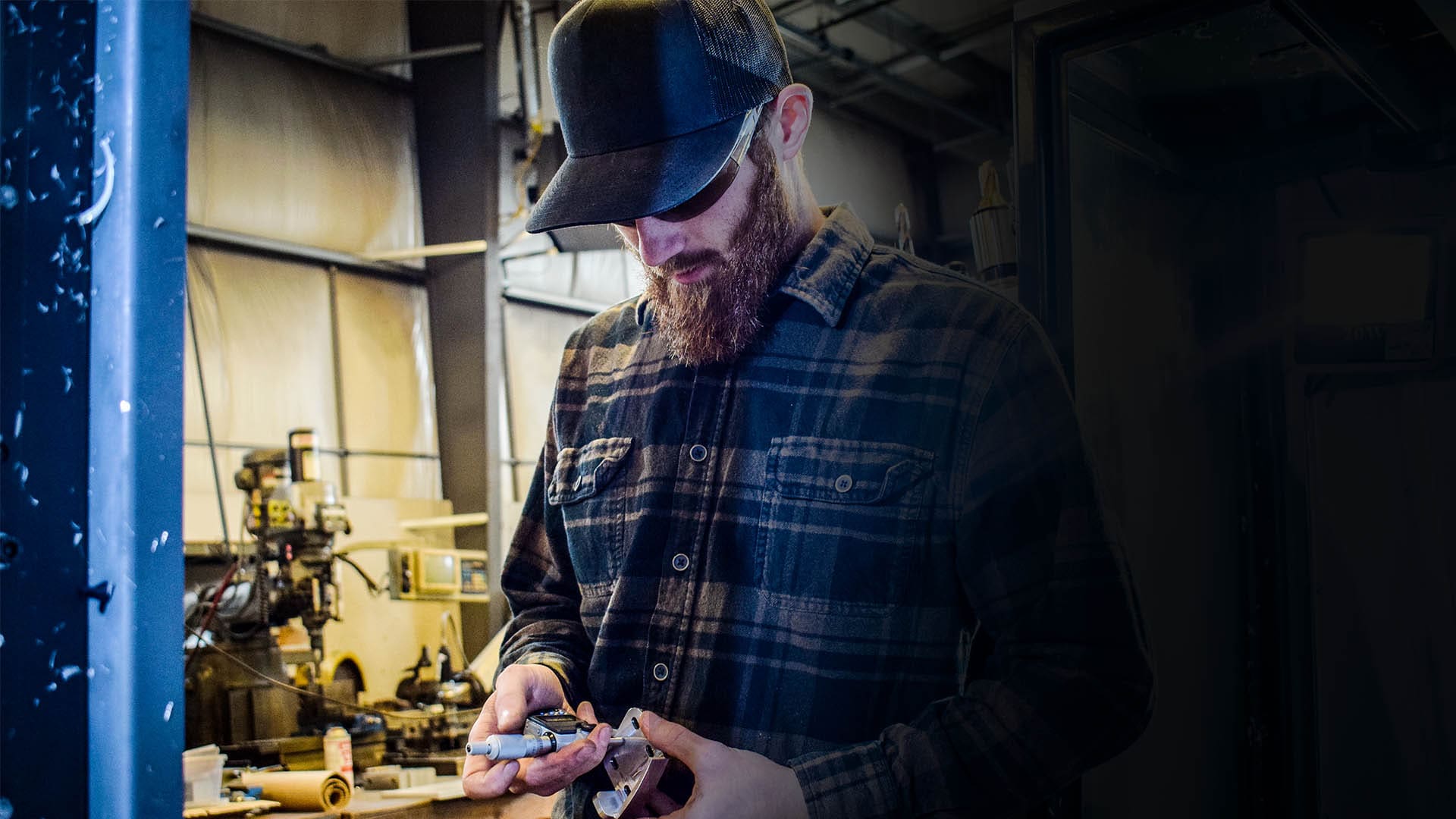 An AJAC Machinist apprentice uses a micrometer to measure a machined part.