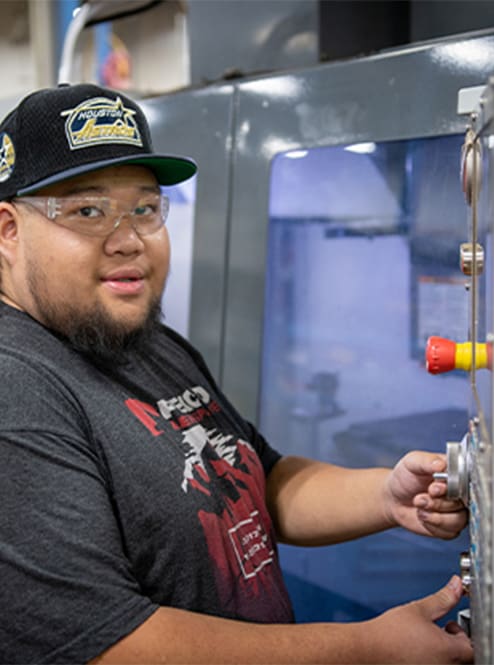 An AJAC apprentice operates a CNC machine on the shop floor.