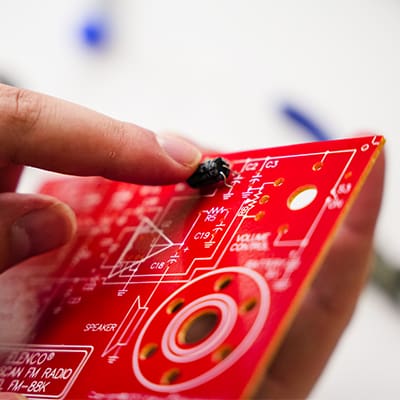 A student in the AJAC Snohomish County Manufacturing Academy program works on soldering components together for a radio project.